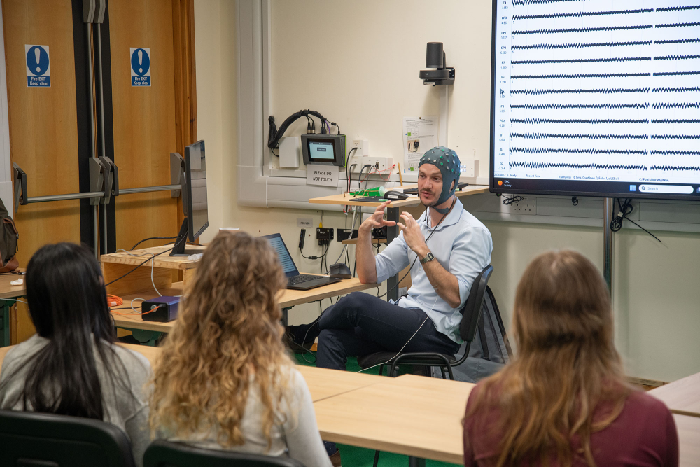 a researcher wearing an EEG talks to the pupils